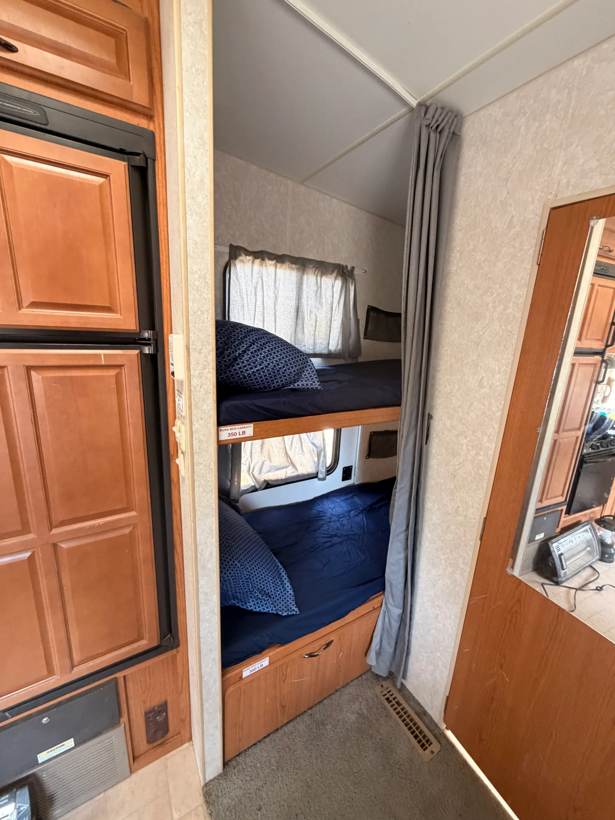 Rear bunkhouse with the bunk bed made up behind a privacy curtain