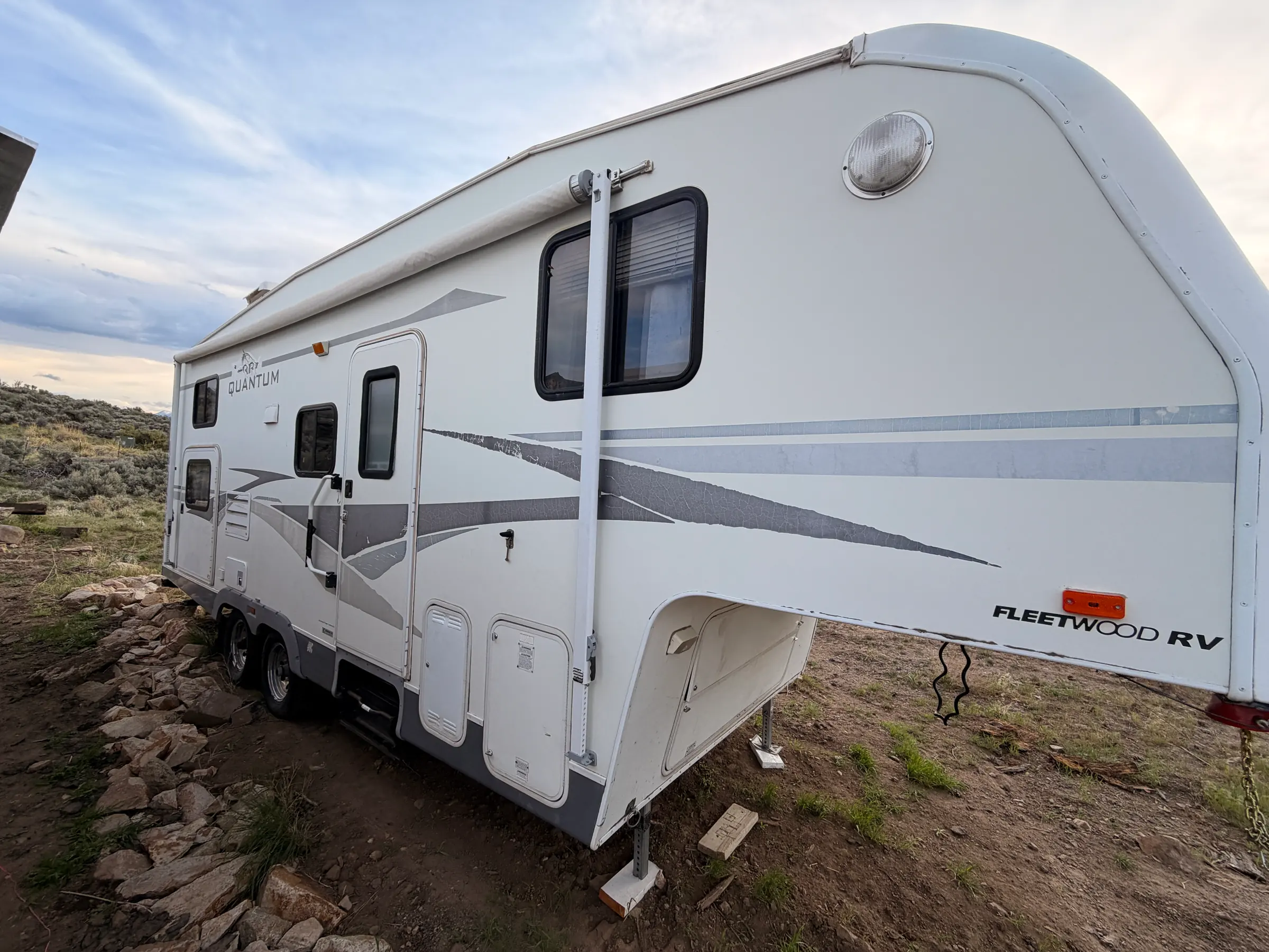 Door side of the fifth wheel with the awning arm extended and the entry steps down