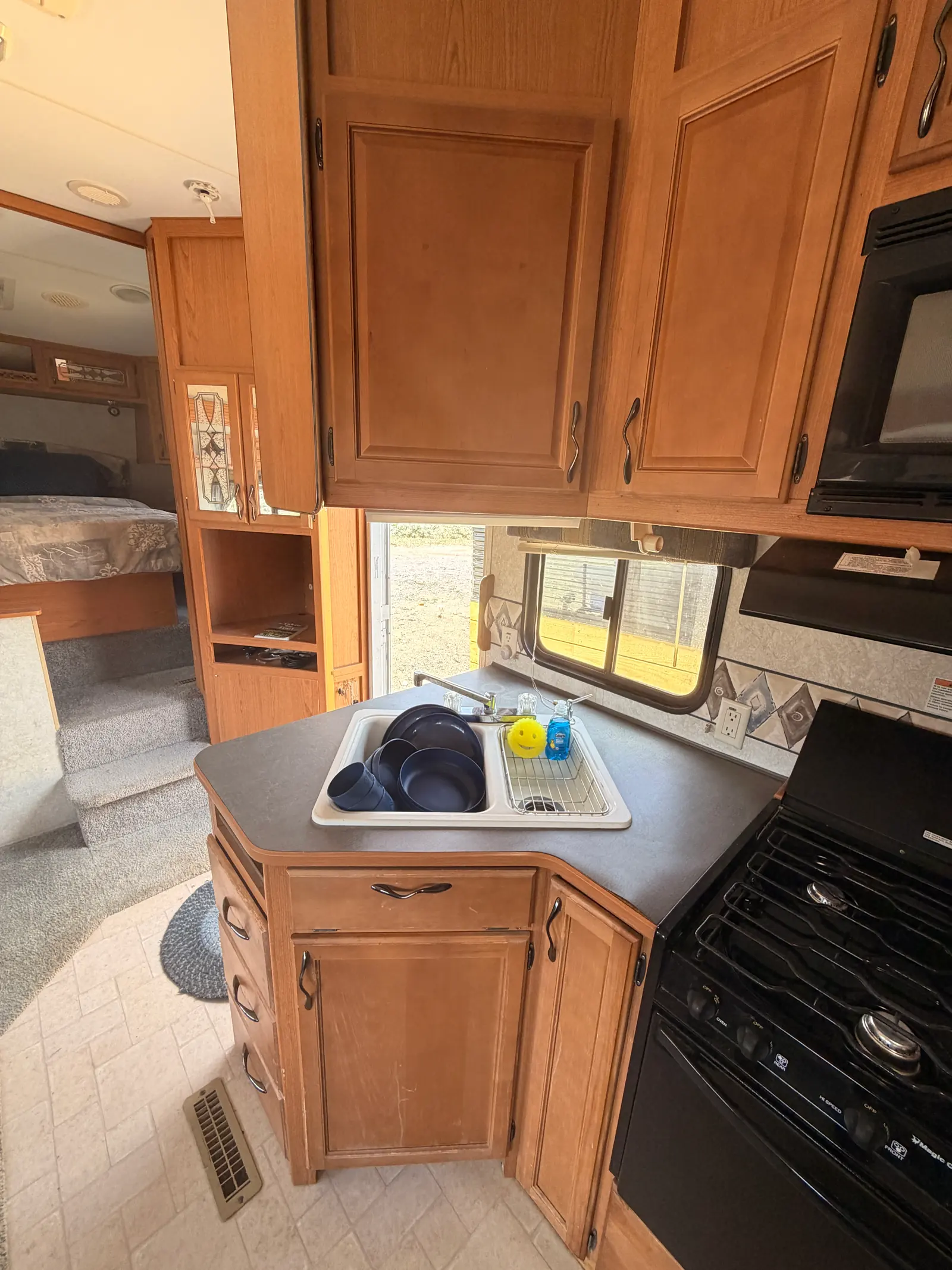 Three-burner gas cooktop and oven beside the microwave and overhead cabinets